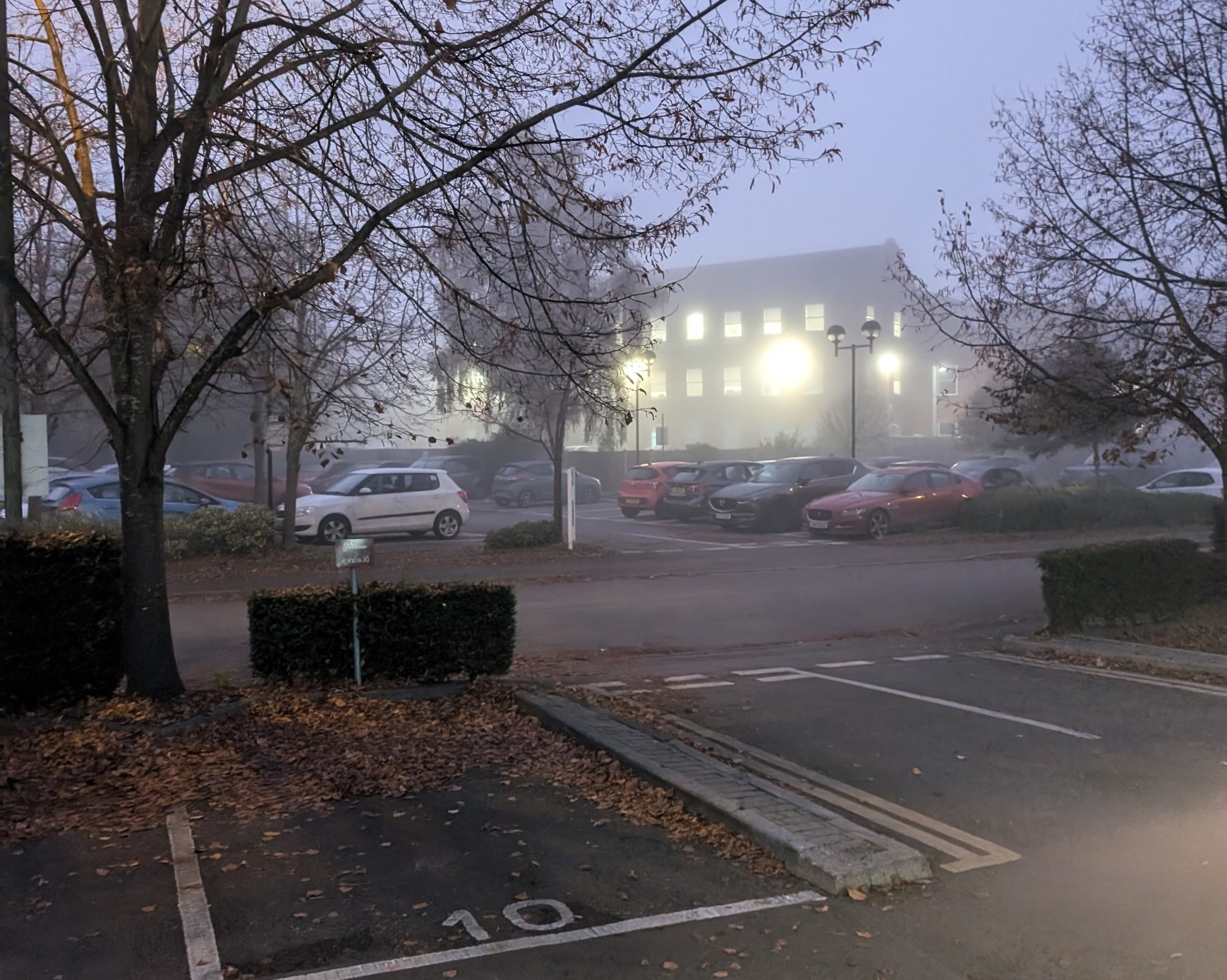 A misty car park on an industrial estate in the evening